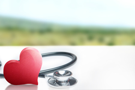 Red heart and a stethoscope on the table with outdoors background. Health day conceptの写真素材