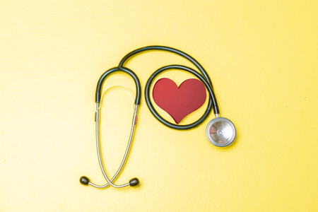 Stethoscope and red heart over yellow color background. Health day conceptの写真素材