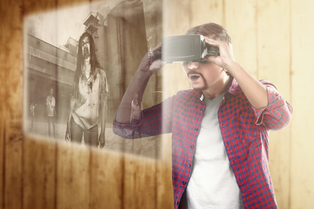 Asian man looking at digital interface with virtual reality device display the horror movies of zombies. Augmented reality technologyの写真素材