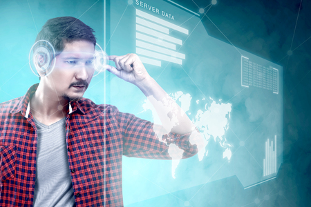 Asian man looking at digital interface with virtual glasses device display the world map, graphic bar and binary code. Augmented reality technologyの写真素材