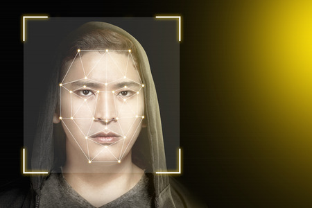Young asian man in black hoodie using face recognition over dark background. Modern technology conceptの写真素材