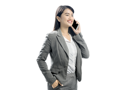 Beautiful asian business woman talking on mobile phone posing isolated over white backgroundの写真素材