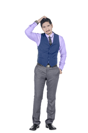 Young asian businessman scratching his head and look confused posing isolated over white backgroundの写真素材