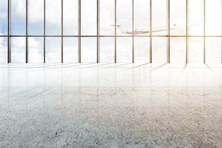 Empty airport hall with window of glass and flying airplane over blue sky backgroundの写真素材