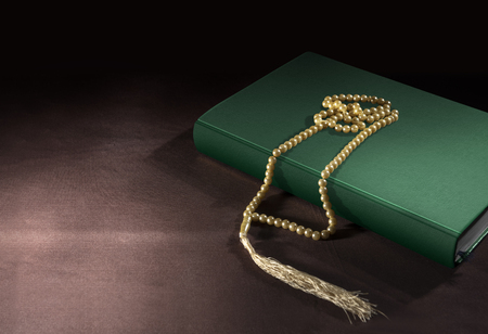 Quran and prayer beads on the table over black backgroundの写真素材