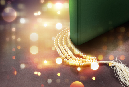 Quran and prayer beads on the table with blurry lights backgroundの写真素材