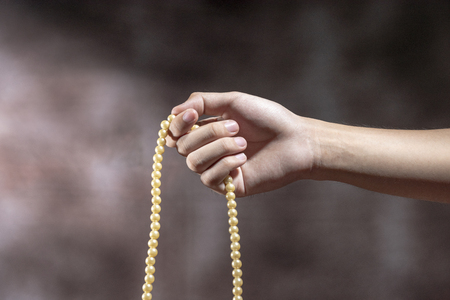 Muslim hands praying with prayer beads over blurry backgroundの写真素材