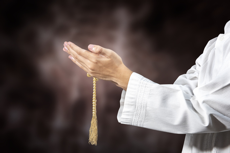 Muslim man praying with prayer beads on his hands over blurry backgroundの写真素材