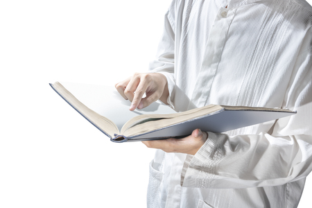 Muslim man standing while reading the quran on his hands isolated over white backgroundの写真素材