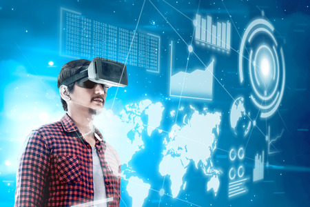 Asian man looking at digital interface with virtual reality device display the world map, graphic bar and binary code. Augmented reality technologyの写真素材