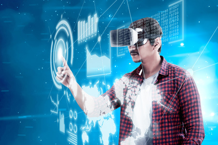 Asian man touching blue sphere on digital interface with virtual reality device display the world map, graphic bar and binary code. Augmented reality technologyの写真素材
