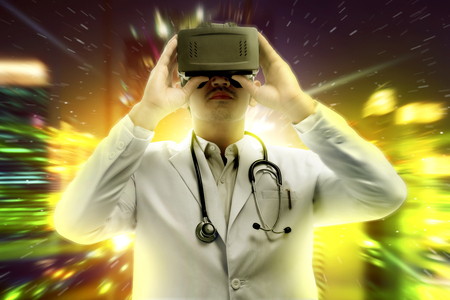 Asian male doctor in white coat and stethoscope using virtual reality device. Augmented reality technologyの写真素材