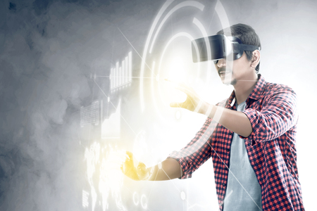 Asian man touching a circle and world map on digital interface with virtual reality device display the world map, graphic bar and binary code. Augmented reality technologyの写真素材