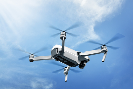 White drone with camera flying in the air over blue sky backgroundの写真素材