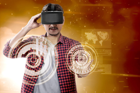 Asian man touching a circle on digital interface with virtual reality device display the world map and binary code. Augmented reality technologyの写真素材