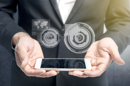 Businessman showing mobile phone on his hand with virtual screen which display the interface of world map and binary code. Digital technology conceptの写真素材