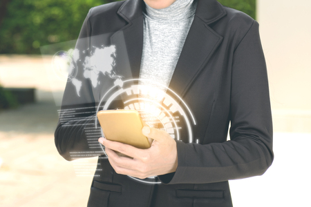 Business woman using mobile phone on her hand with virtual screen which display the interface of world maps and binary code. Digital technology conceptの写真素材