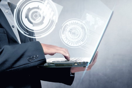 Businessman holding the laptop with virtual screen which display the interface of world maps and binary code. Digital technology conceptの写真素材