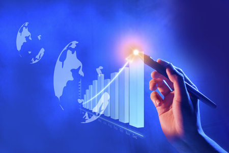 Business hand with marker draw a increases financial chart on virtual screen which display the interface of globe. Digital technology conceptの写真素材