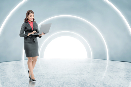 Side view of asian asian business woman holding laptop with his hand while walking on the office corridor. Future technology conceptの写真素材