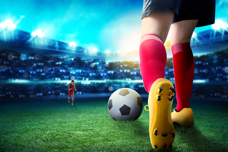 Rear view of football player woman dribbling the ball on and dealing with her opponent on the football field at stadiumの写真素材