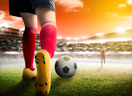 Rear view of football player woman dribbling the ball on and dealing with her opponent on the football field at stadiumの写真素材