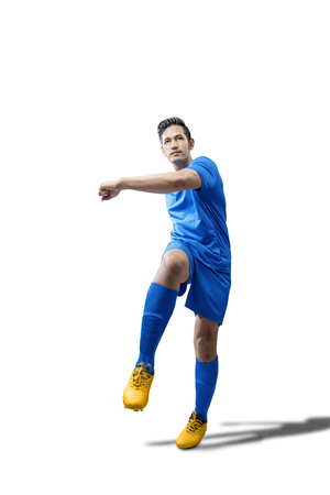 Portrait of asian football player man in blue jersey with kicking the ball position isolated over white backgroundの写真素材