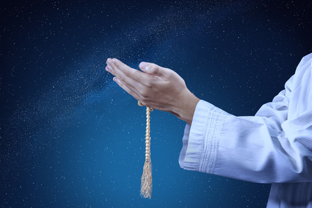 Muslim man praying with prayer beads on his hands at outdoor with night scene backgroundの写真素材