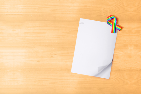 White paper with clip and ribbon with rainbow flag on wooden table. White paper for copyspace. LGBT conceptの写真素材
