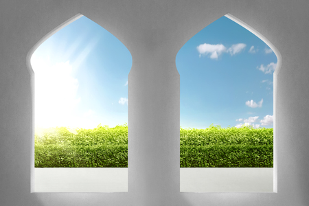 Beautiful arches of mosque with garden views and sunlight rays over blue sky backgroundの写真素材