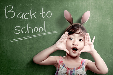 Asian student girl with funny expression standing with chalkboard background. Back to School conceptの写真素材