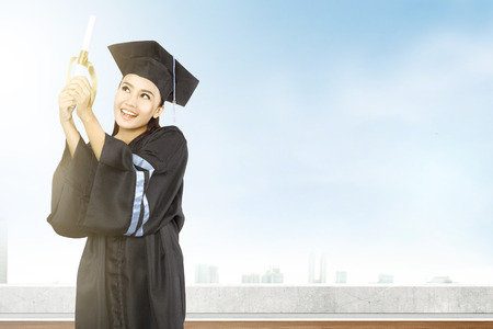 Asian woman in mortarboard hat and diploma graduating from college. Graduation conceptの写真素材