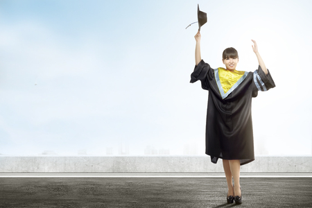 Asian woman holding mortarboard cap celebrate graduation from college. Graduation conceptの写真素材