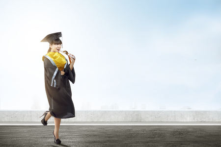 Asian woman in mortarboard hat and diploma graduating from college. Graduation conceptの写真素材