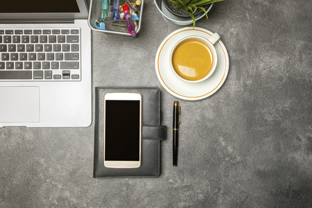 Top view of business desk with laptop, coffee, potted plant, notebook, mobile phone and business accessories on the officeの写真素材
