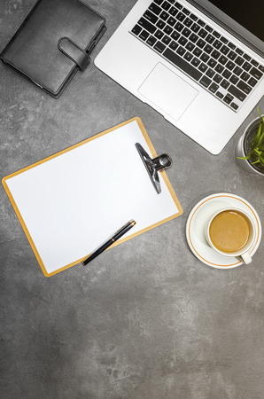 Top view of business desk with laptop, coffee, potted plant, notebook and clipboard on the officeの写真素材