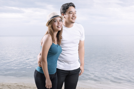 Asian romantic couple with woman in hat relax and walking on the beach. Summer vacationの写真素材