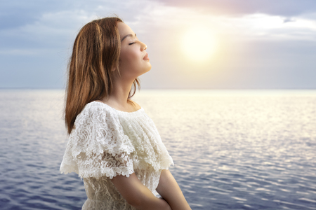 Asian girl in white outfit relax and enjoying the sunset on the beach. Summer vacationの写真素材