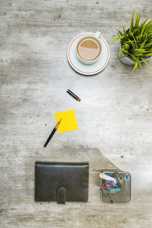 Top view of business desk with coffee, potted plant, notebook, notes paper and business accessories on the officeの写真素材