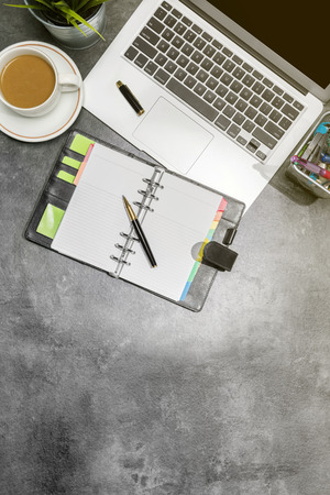 Top view of business desk with laptop, coffee, potted plant, notebook and business accessories on the officeの写真素材
