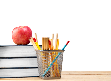 Pile of books with apple and pencils in basket container on wooden table isolated over white background. Back to School conceptの写真素材