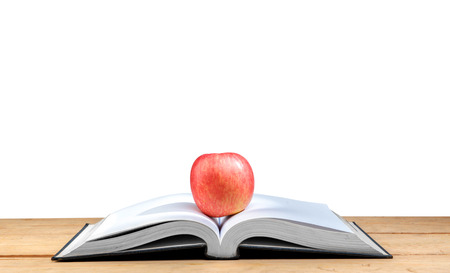 Apple on the middle of opened book on wooden table isolated over white background. Back to School conceptの写真素材