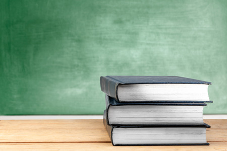 Pile of books on wooden table with chalkboard background. Back to School conceptの写真素材