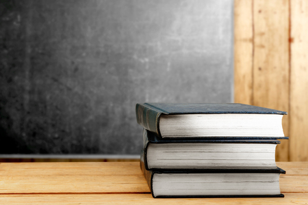 Pile of books on wooden table with blackboard background. Back to School conceptの写真素材