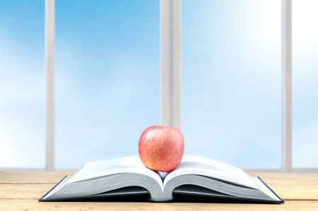 Apple on the middle of opened book on the wooden table. Back to School conceptの写真素材