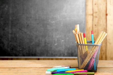 Pencils in basket container and colorful crayons on the wooden table with blackboard background. Back to School conceptの写真素材