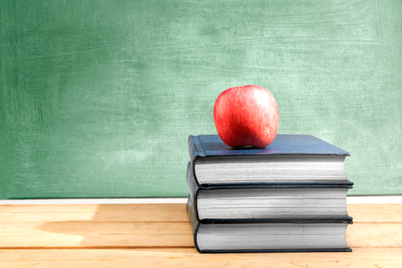 Pile of books with apple on the wooden table with chalkboard background. Back to School conceptの写真素材