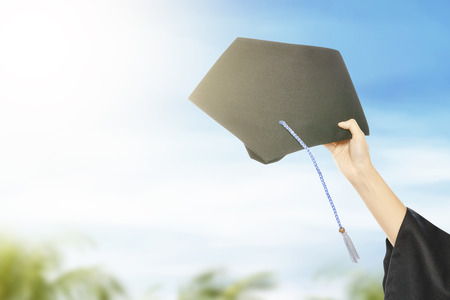 Hand holding graduation hat with blue sky background. Graduation conceptの写真素材