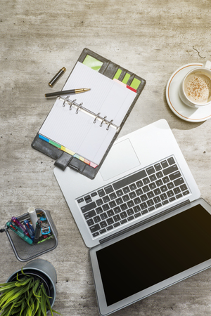 Top view of business desk with laptop, coffee, potted plant, notebook and business accessories on the officeの写真素材