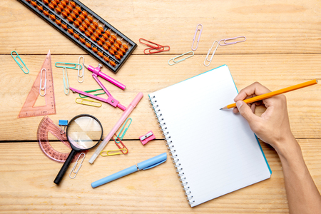 Student writing in notebook with school supplies and stationery on the wooden table. Back to School conceptの写真素材